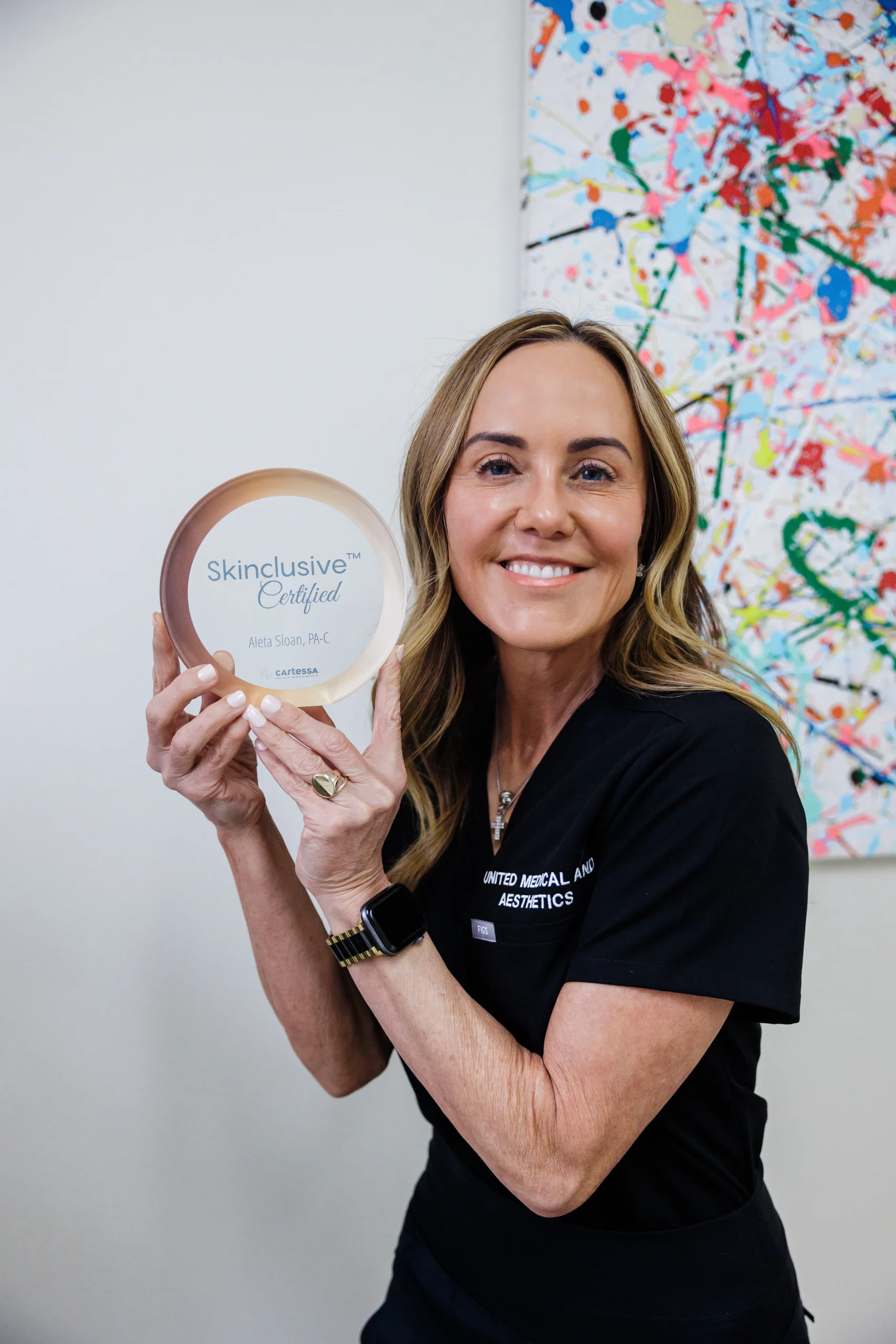 A woman holding a Skinclusive Certified award, smiling proudly | United Medical And Aesthetics in Wilmington, NC