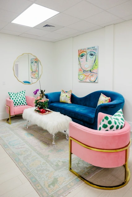 A room with a blue couch and pink chairs | United Medical And Aesthetics in Wilmington, NC